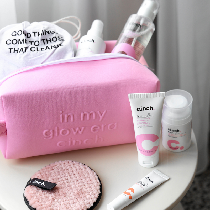 cinch all set, cleanse + glow, spray + glow inside the pink pouch, lip balm, face pad, sleep + glow, pump + glow in the table surface